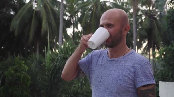 Młody Mężczyzna Pije Gorący Napój Tle Pięknych Wysokich Palm — Wideo stockowe