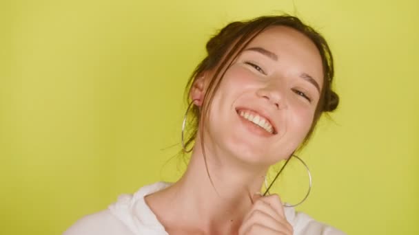 幸せな女性は カメラを見て 彼女の髪と笑顔を再生します 黄色の背景が孤立 空気のキス 高品質4K映像 — ストック動画