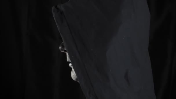 有化妆骷髅和黑色头罩的男人在黑暗的背景 骷髅在看着摄像机 万圣节或恐怖主题 优质4K视频 — 图库视频影像