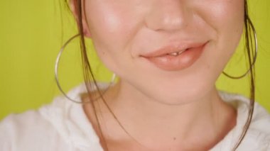 Parlak kadın dudaklarının aşırı yakın çekimi. Stüdyoda izole edilmiş sarı bir arka planda kız öpüyor ve gülümsüyor. Sevgi. Yüksek kalite 4k görüntü