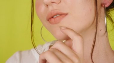 Parlak kadın dudaklarının aşırı yakın çekimi. Stüdyoda izole edilmiş sarı bir arka planda kız öpüyor ve gülümsüyor. Sevgi. Yüksek kalite 4k görüntü