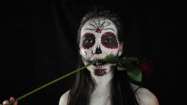 Cadılar Bayramı makyajı. Güllü kız. Karanlık bir arka planda korkunç renkli Cadılar Bayramı makyajlı genç bir kadının portresi.. 