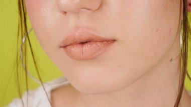 Parlak kadın dudaklarının aşırı yakın çekimi. Stüdyoda izole edilmiş sarı bir arka planda kız öpüyor ve gülümsüyor. Sevgi. Yüksek kalite 4k görüntü