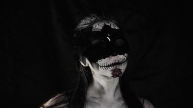 Meksika Ölüler Günü. Şeker kafalı, Cadılar Bayramı makyajlı genç bir kadın kameraya bakıyor. Kadın yüzündeki maskeyi çıkartıyor. Mutlu Cadılar Bayramı. Yüksek kalite 4k video