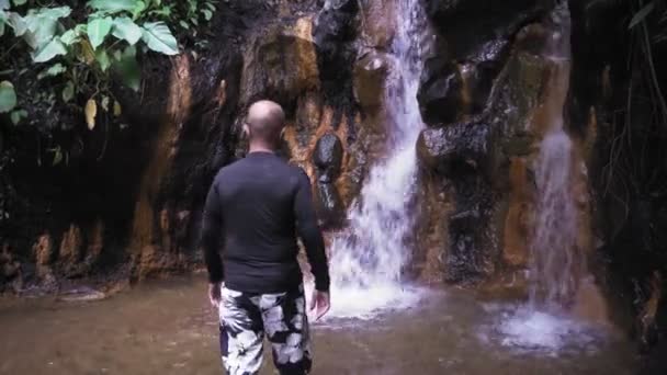 一个男人看着丛林中的一个小瀑布 — 图库视频影像