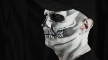 Cadılar Bayramı için makyaj iskeleti. Karanlık bir arka planda insan iskeleti. Adam başka tarafa bakıyor.