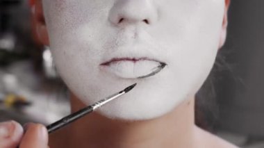 Ressam bayramdan önce bir kıza makyaj yapar. Bir adam bir yüz çizer. Mutlu Cadılar Bayramı