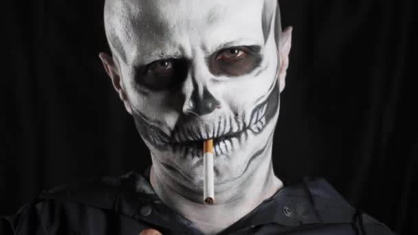 Άντρας Σκελετό Μακιγιάζ Και Μαύρη Κουκούλα Σκούρο Φόντο Σκελετός Καπνίζει — Αρχείο Βίντεο