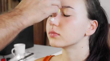 Ressam bayramdan önce bir kıza makyaj yapar. Bir adam bir yüz çizer. Mutlu Cadılar Bayramı