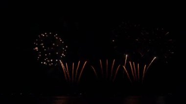 Gece gökyüzünde Bokeh ışıkları olan büyük, altın gibi havai fişekler. Parlayan havai fişekler