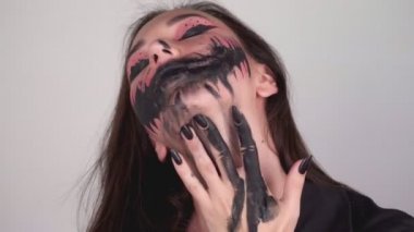 Seksi kadın yüzünün her yerine boya bulaştırıyor. Cadılar bayramı için makyajı yıkayan kadın. Yüksek kalite 4k görüntü