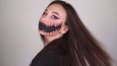 Cadılar Bayramı maskeli bir kadın kameraya dönüyor. Gri arka plan. Yüksek kalite 4k görüntü