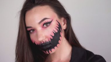 Yüzüne boya bulaştıran seksi kadın Cadılar Bayramı için makyajını siliyor.