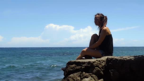 Jovem Mulher Senta Uma Rocha Desfruta Sol Mar Dia Quente — Vídeo de Stock