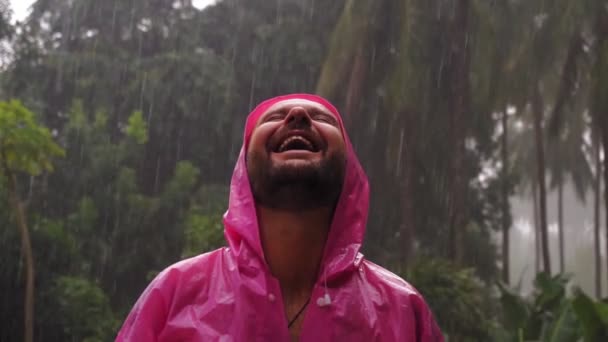 Homem Adulto Com Uma Capa Chuva Rosa Desfruta Chuva Tropical — Vídeo de Stock