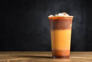 Portakal suyu, karamel, buz ve kahveden oluşan yaz kokteyli ahşap bir masada fotokopi alanı olan plastik bir bardakta..