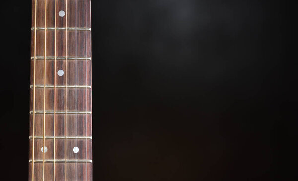 Guitar neck and strings close up on a black background