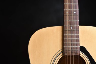 Metal telli akustik hafif ahşap gitar koyu bir arkaplana karşı yakın plan ve boşluğu kopyala