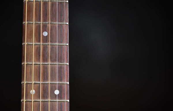 Guitar neck and strings close up on a black background