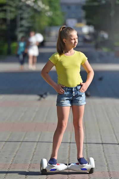 Mädchen reitet allein auf einem Hoverboard in einem Park an einem sonnigen Sommertag — Stockfoto