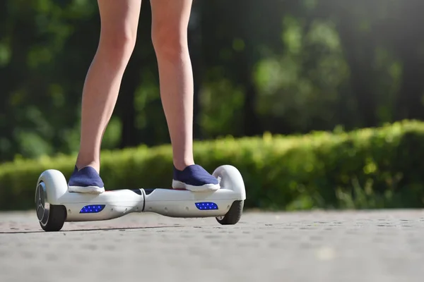 Kaki seorang anak perempuan dan hoverboard di latar belakang taman musim panas — Stok Foto