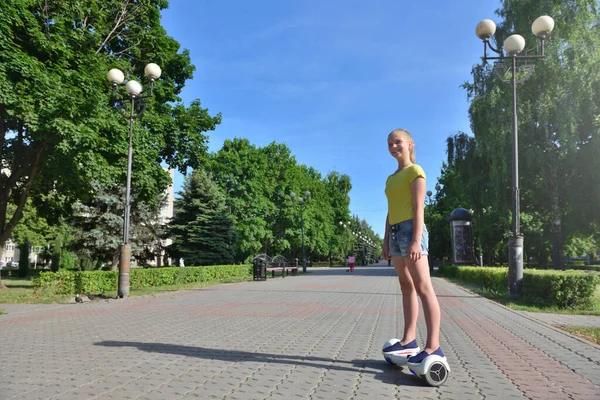 Gelukkig meisje kind rijden een hoverboard in zomer park — Stockfoto
