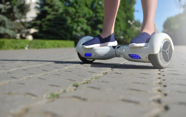 Elektrisches Hoverboard und Beine eines Mädchens auf dem Hintergrund eines Sommerparks — Stockfoto