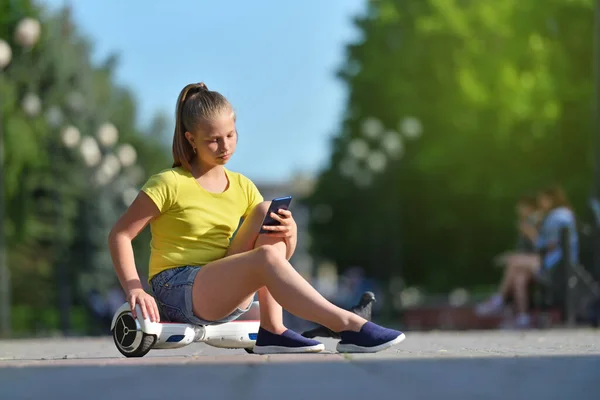 Meisje kind leest bericht op een smartphone tijdens het wandelen in het park — Stockfoto