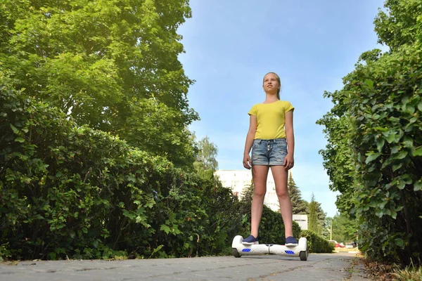 Een meisje kind rijdt een elektrische hoverboard in een park op de stoep — Stockfoto