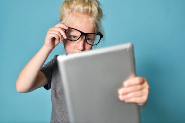 Gözlüklü kız, tablet bilgisayarda oynuyor ve görme zorluğu çekiyor.