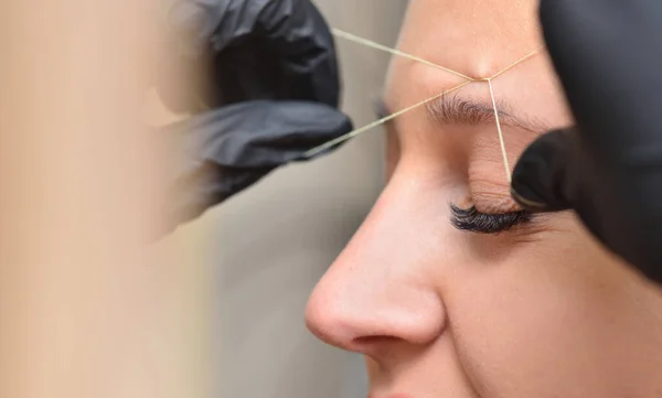 Eyebrow correction procedure with thread and woman face close up