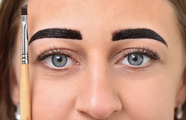 Junge Frau färbt ihre Augenbrauen mit Henna und hält einen Pinsel neben ihr Gesicht — Stockfoto