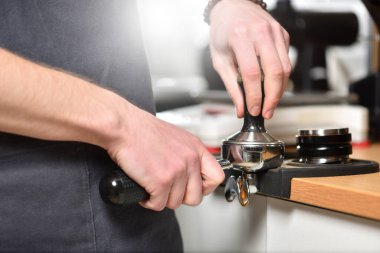 Barista kahve yapıyor, elinde bir filtre tutuyor ve kahvesini ütülüyor..