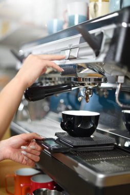 Genç bayan barista büyük bir kahve makinesinde kahve yapıyor, elleri kapalı. Küçük işletme kavramı ve bir öğrenci için çalışma.