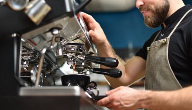 Genç bir barista büyük bir kahve makinesinde kahve yapıyor..