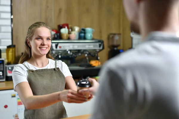 Egy fiatal barista lány kávét árul, és odaadja egy ügyfélnek. Kisvállalkozói koncepció — Stock Fotó