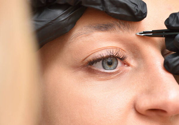 Крупный план глаза и брови молодой женщины и процедура коррекции бровей.