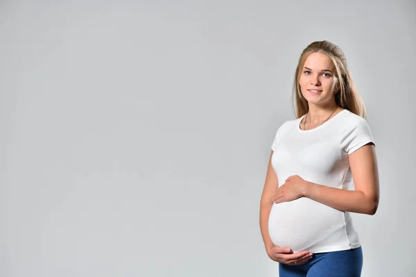 Happy kobieta w ciąży wiek 20 lat na szarym tle — Zdjęcie stockowe
