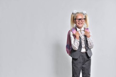 Dişi olmayan neşeli liseli kız. Gri arka planda gülümsüyor. Fotokopi alanı var.