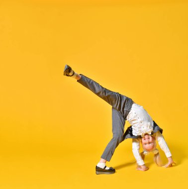 Aktif mutlu anaokulu kızı sarı arka planda oynaşıyor.