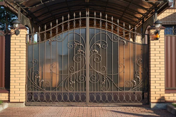 Puertas de metal forjado con líneas adornadas para entrar en una casa privada —  Fotos de Stock
