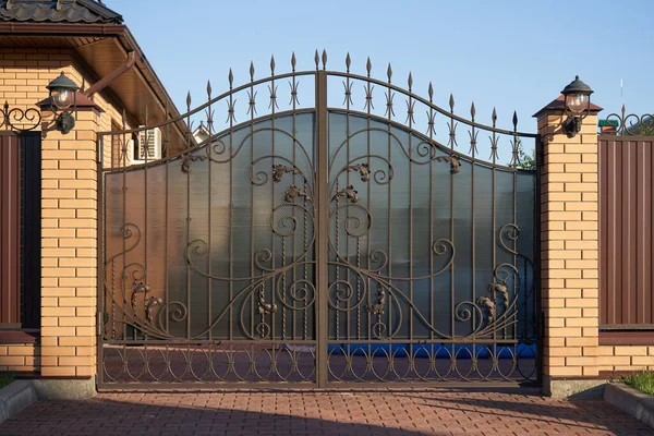 Puertas de metal forjado con líneas adornadas para entrar en una casa privada — Foto de Stock