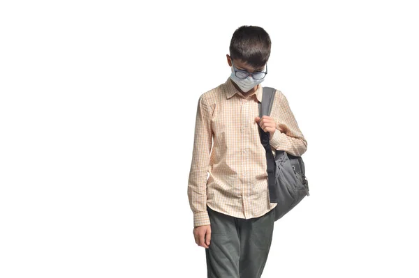 Sad skolpojke bär glasögon och skyddsmask på vit isolerad bakgrund — Stockfoto
