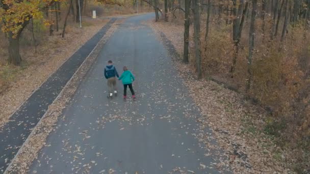 男子和女子在秋季公园滑旱冰，手牵手，鸟瞰 — 图库视频影像