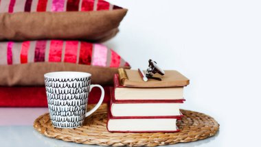 Konforlu ev dekorasyonu: bir fincan kahve, kitap yığını, yastıklar ve beyaz bir masanın üzerindeki ekose. Uzaktan eğitim. Karantina konsepti: