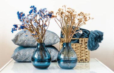 Konforlu ev dekorasyonu: yastık, ekose, odadaki beyaz rafta çiçekli mavi vazo. Karantina konsepti: