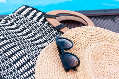 Eski yaz hasır hasır hasır plaj çantası, güneş gözlükleri, yüzme havuzunun yanındaki şapka, tropikal arka plan.