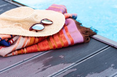 Eski yaz hasır hasır hasır hasır plaj şapkası, güneş gözlükleri, yüzme havuzunun yakınındaki sahte plaj giysileri, tropikal arka plan.