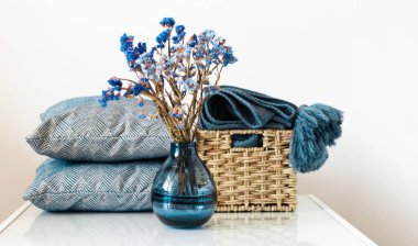 Konforlu ev dekorasyonu: yastık, ekose, odadaki beyaz rafta çiçekli mavi vazo. Karantina konsepti: