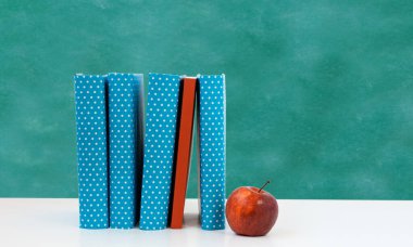 Okula, kitap yığınına ve boş yeşil okul yönetim kurulu geçmişine sahip kırmızı elmaya. Uzaktan eğitim. Karantina konsepti: